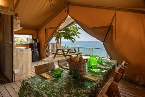 a dining table in a tent with a view of the ocean at Camping Village Riva Blu in Padenghe sul Garda