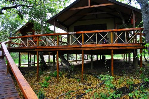 a tree house with a wooden deck in front of it at Lion Tree Top Lodge in Guernsey Nature Reserve
