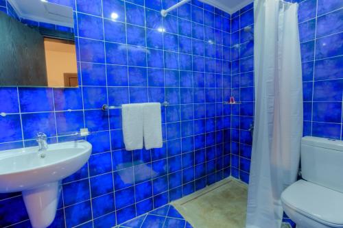 La salle de bains est pourvue de carrelage bleu, de toilettes et d'un lavabo. dans l'établissement Porto Sokhna Apartment powered By Amer-Group Family Only, à Ain Sokhna