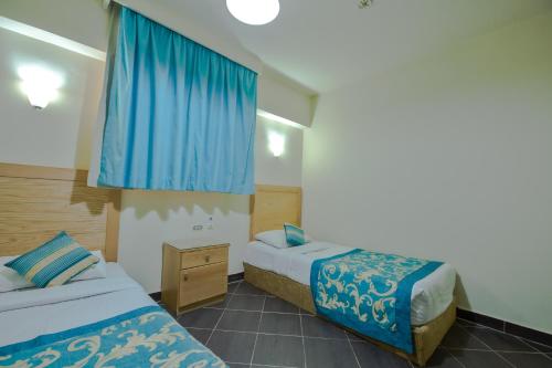 une chambre d'hôtel avec deux lits et des rideaux bleus dans l'établissement Porto Sokhna Apartment powered By Amer-Group Family Only, à Ain Sokhna