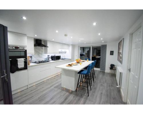 a kitchen with a white counter and blue chairs at Ideal Lodgings in Baxenden in Accrington