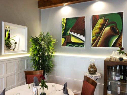 a dining room with a table and a piano on the wall at L'EMBLEME - BOUTIQUE HOTEL in Beaurepaire