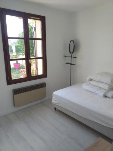 a white bedroom with a bed and a window at La fadette in Argy