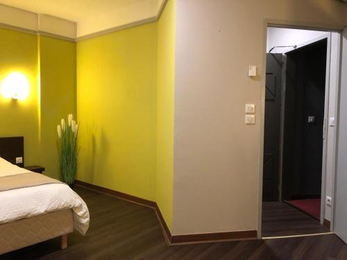 a bedroom with yellow walls and a bed and a door at L'EMBLEME - BOUTIQUE HOTEL in Beaurepaire