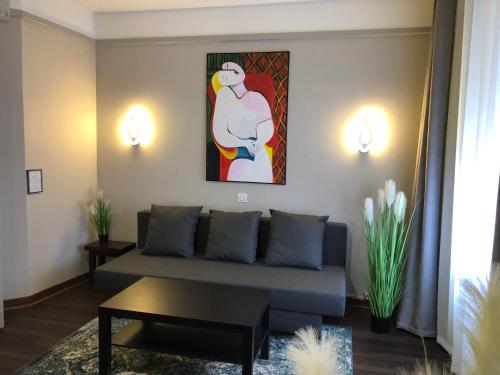 a living room with a couch and a painting on the wall at L'EMBLEME - BOUTIQUE HOTEL in Beaurepaire