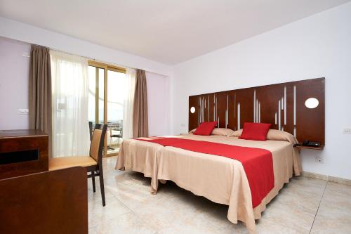 a bedroom with a large bed with a red blanket at Kn Aparthotel Columbus in Playa de las Americas