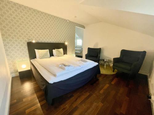 a bedroom with a large bed and two chairs at First Hotel Witt in Kalmar