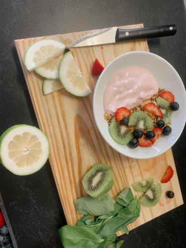 a bowl of yogurt and fruit on a cutting board at De Haas Luxury Living at Villa Grande in Stellenbosch