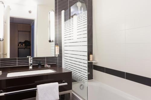 une salle de bain avec un lavabo et un miroir dans l'établissement Novotel Bordeaux Centre Gare Saint Jean, à Bordeaux
