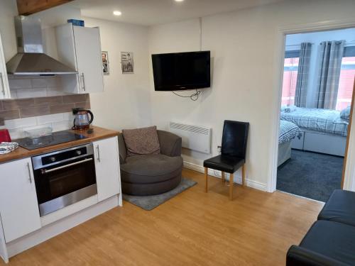 a kitchen and living room with a couch and a tv at Apartment with Roof Terrace close to City Centre in Cardiff