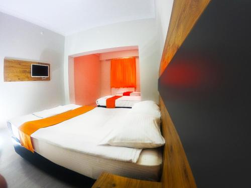 2 Betten in einem kleinen Zimmer mit orangefarbenen Vorhängen in der Unterkunft ANKARA OTEL EVREN in Ankara