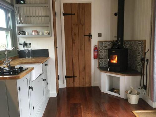 - une cuisine avec un poêle à bois dans une chambre dans l'établissement Bluebell shepherds Hut, à Rolvenden