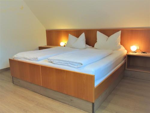 Gästehaus Jutta / Pension Link في فلادونغن: سرير كبير في غرفة بها مصباحين