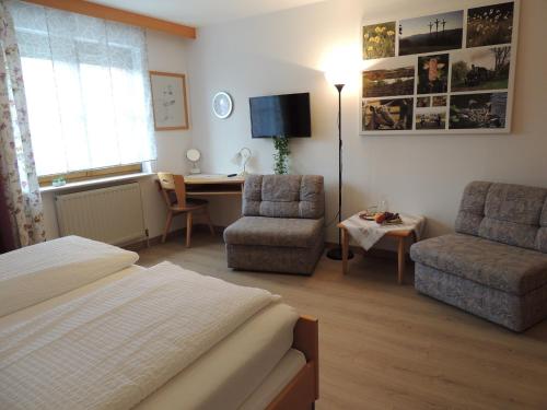 a bedroom with a bed and a chair and a desk at Gästehaus Jutta / Pension Link in Fladungen
