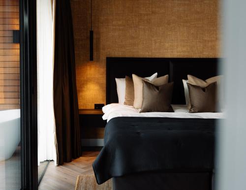 a bedroom with a black bed with pillows at Haven Lake Village in Kortenhoef
