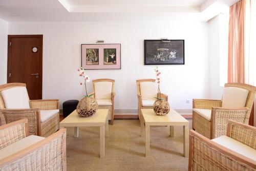 a waiting room with chairs and vases on tables at Hotel Dom Nuno in Santiago do Cacém