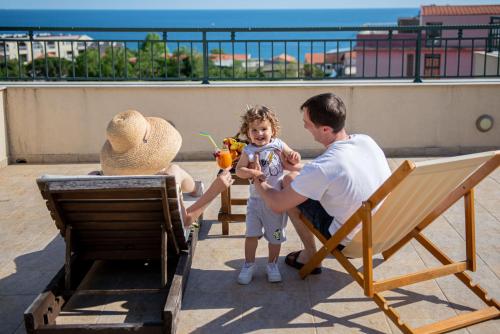 a man and a woman and a child sitting on a balcony at Guest House Medin in Petrovac na Moru
