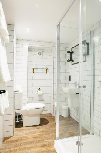 a white bathroom with a toilet and a sink at Crown Hotel in Stamford