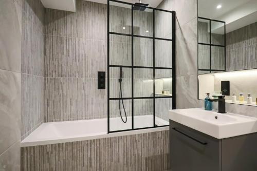 een badkamer met een douche, een wastafel en een bad bij Portfolio Apartments - Welwyn Town Centre in Welwyn Garden City
