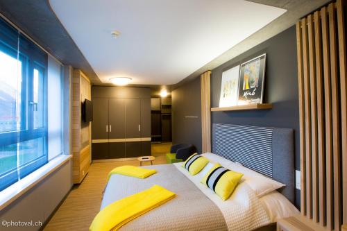 a bedroom with a bed with yellow pillows and a window at Martigny Boutique-Hôtel in Martigny-Ville