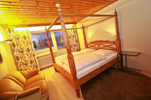a bedroom with a canopy bed and a chair at Pension KaraMia in Fichtelberg