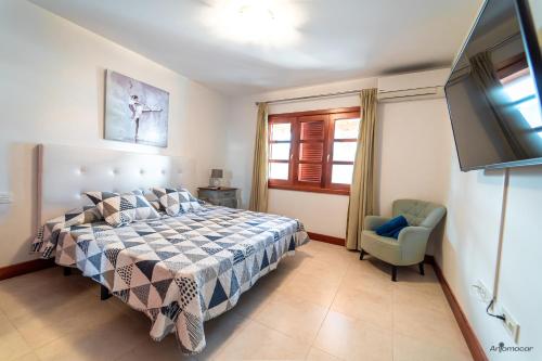 a bedroom with a bed and a chair and a television at Luxury Villas Anjomacar in Teguise