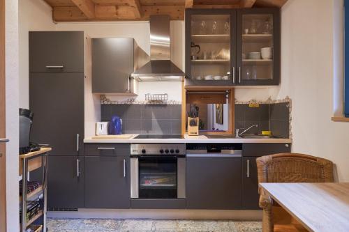 cocina con armarios grises y horno en Bio-Ferienhaus-Eifel, en Rott