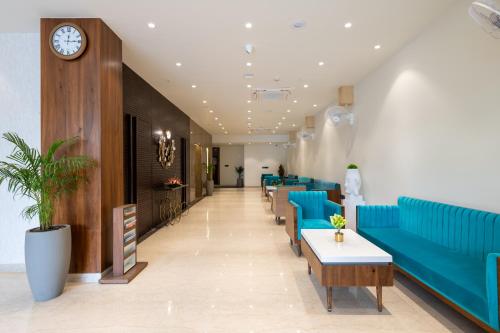 a lobby with blue couches and tables and a clock at Hotel Regal Grand in Bhopal