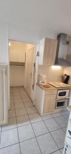 Il comprend une cuisine dotée d'appareils électroménagers blancs et de carrelage. dans l'établissement Les embruns, à Bormes-les-Mimosas