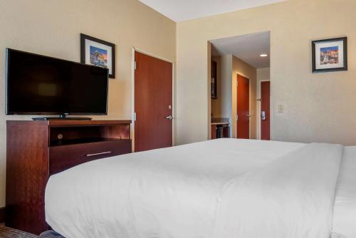 a bedroom with a large white bed and a flat screen tv at Comfort Inn & Suites in Clinton