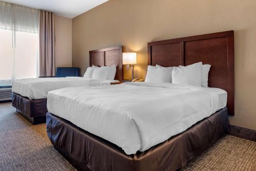 a hotel room with two beds with white sheets at Comfort Inn & Suites in Clinton