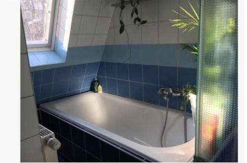 y baño con bañera y azulejos azules. en Altbauwohnung Stuttgart Ost, en Stuttgart