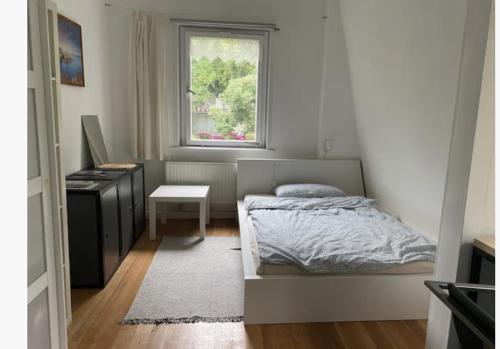 1 dormitorio con cama, escritorio y ventana en Altbauwohnung Stuttgart Ost, en Stuttgart