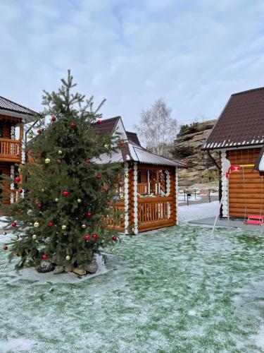 a christmas tree in the yard of a log cabin at Eco hotel & restaurant "SKALA" in Borovoye