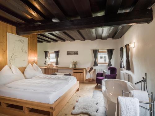 a bedroom with a large bed and a bath tub at Chalet Wolfbachgut in Taxenbach