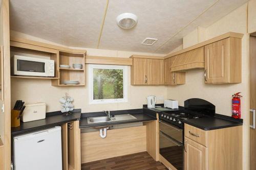 a small kitchen with wooden cabinets and a sink at Whitecliff Bay Holiday Park in Bembridge