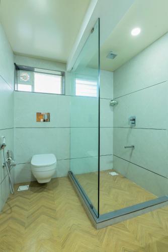 a bathroom with a toilet and a glass shower at Gold Beach Villa in Daman