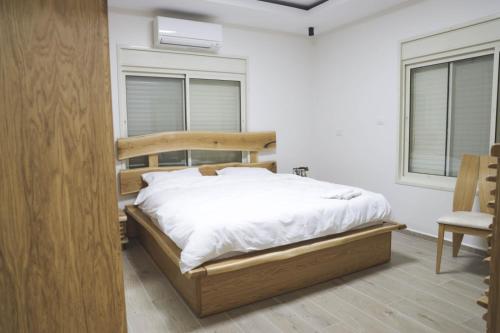 - une chambre avec un lit, une chaise et deux fenêtres dans l'établissement נווה חרמון, à Majdal Shams