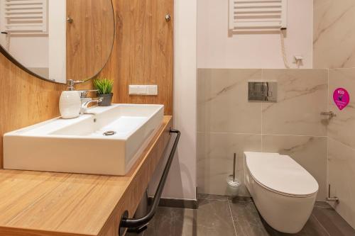 a bathroom with a sink and a toilet and a mirror at VacationClub – Jantaris Apartament A 35 in Mielno