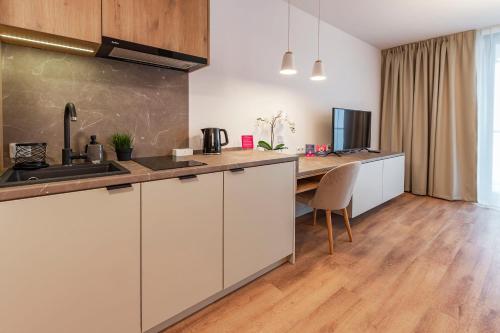 a kitchen with white cabinets and a wooden floor at VacationClub – Jantaris Apartament A 35 in Mielno