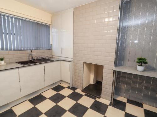 a kitchen with a checkered floor and a fireplace at 55 Marine Road in Abergele