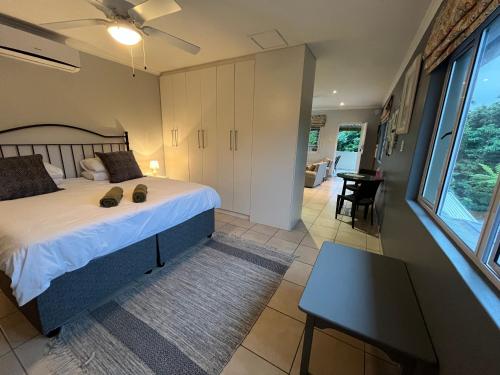 a bedroom with a bed and a desk and a table at PIGEONWOOD Forest Cottage in Ballito