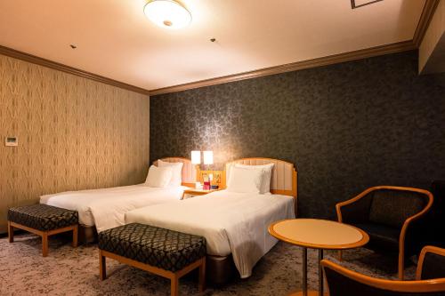 a hotel room with two beds and a table and chairs at ANA Crowne Plaza Matsuyama by IHG in Matsuyama