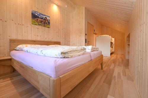 ein Schlafzimmer mit einem Bett in einem Holzzimmer in der Unterkunft Ferienhof Landerleben in Egg