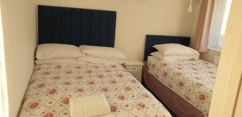 a small bedroom with two beds and a headboard at Tivoli Bungalow in Weston-super-Mare
