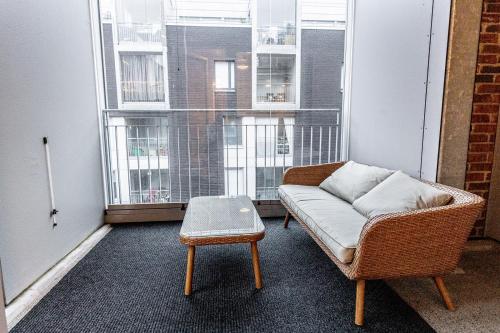 a couch and a stool in a room with windows at SleepWell Apartment Rio with private sauna and parking in Helsinki