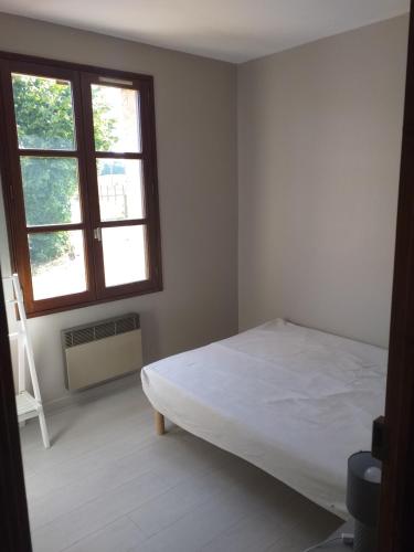 a white bedroom with a bed and two windows at La fadette in Argy