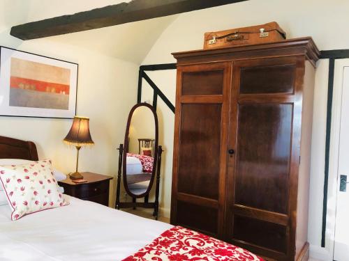 a bedroom with a large wooden cabinet next to a bed at The Blue Cow in Fenstanton