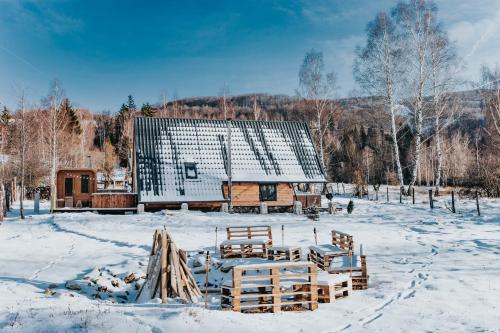 a barn with snow on the ground in front of it at Acasă Straja - Casa Vintage in Lupeni