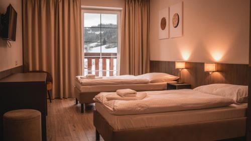 a hotel room with two beds and a window at Wellness Penzión Smerdžonka - KÚPELE PIENINY in Červený Kláštor